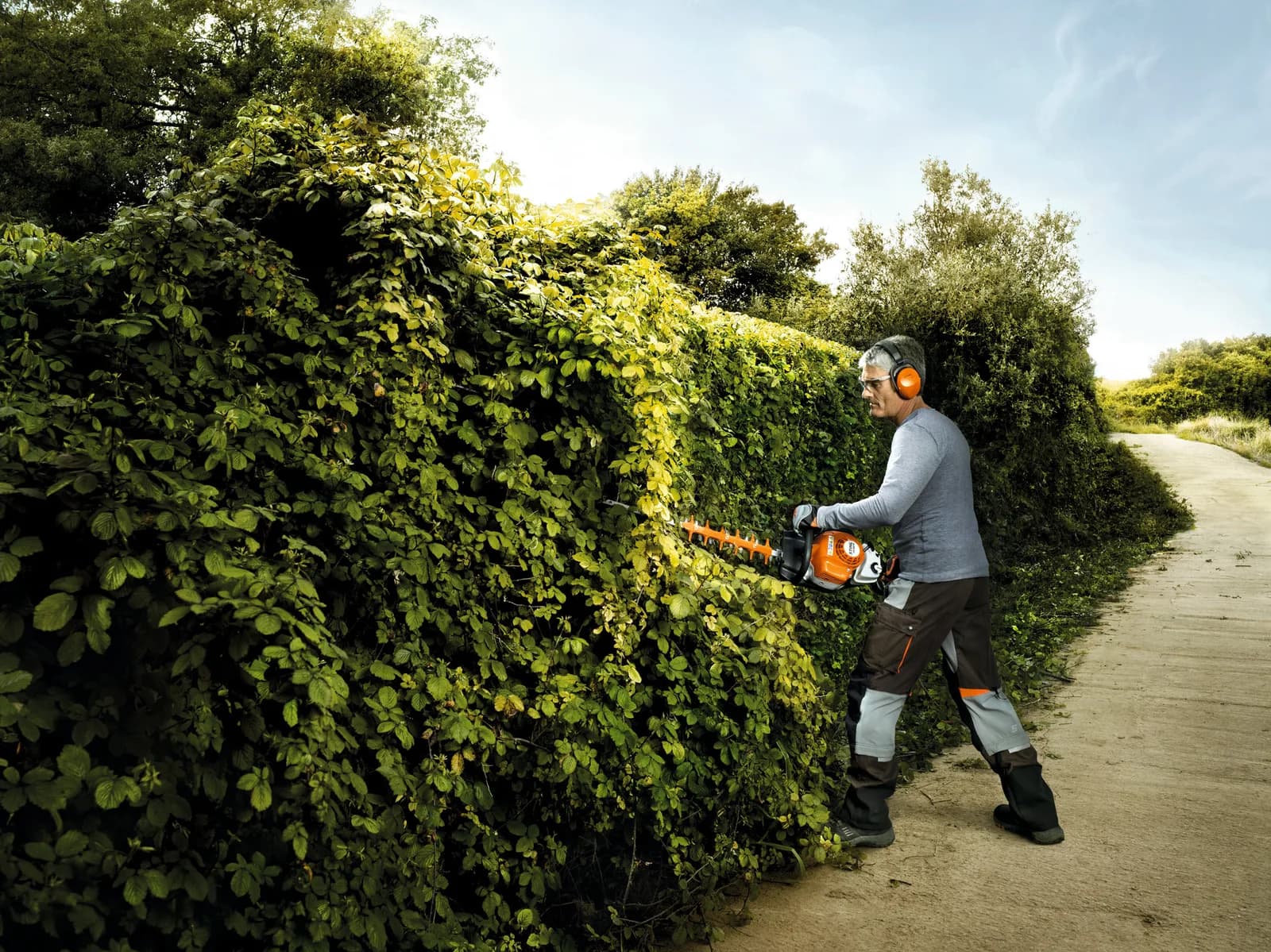 Jardinero dando forma a un seto con un cortasetos STIHL